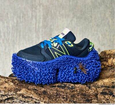 Futuristische hardloopschoenen met het New Balance logo en enorme dikke blauwe zolen met haakjes, waar zaden en plantenmateriaal aan hechten, ontworpen door Kiki Grammatopoulos.